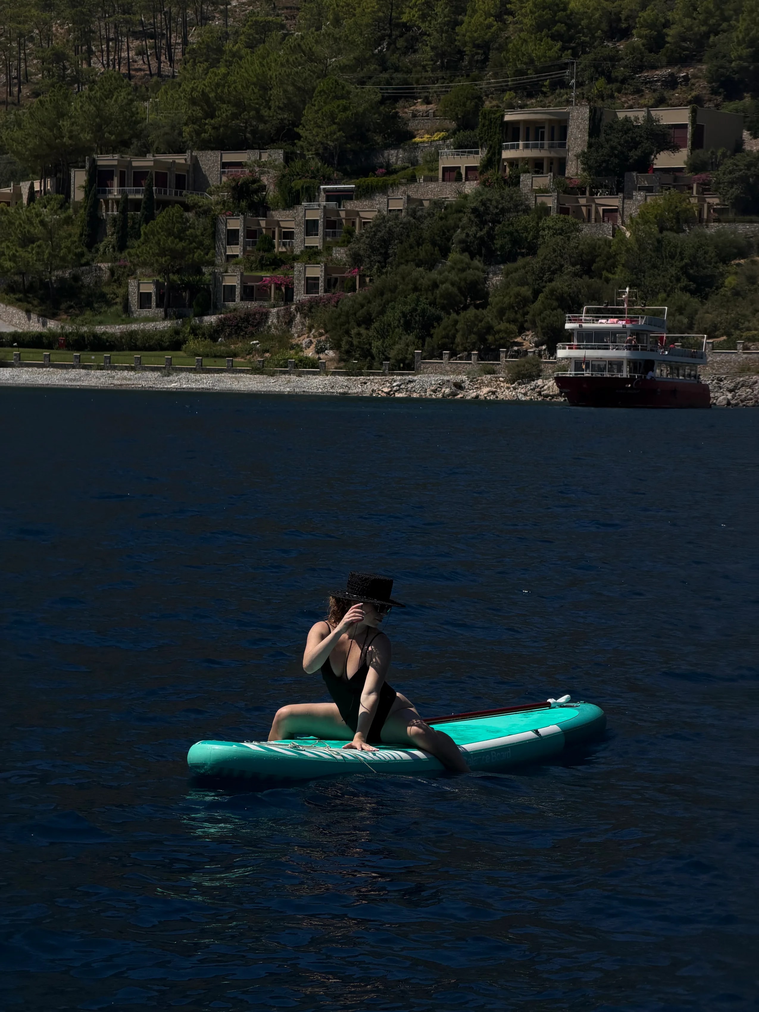 Девушка сидит на SUP-доске на воде у берега