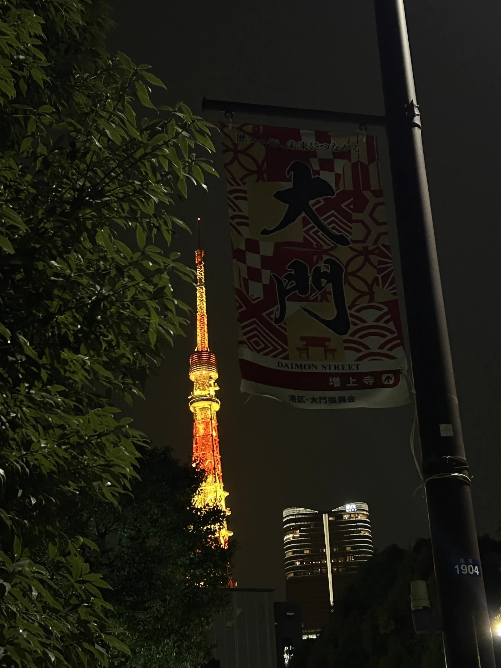 Подсвеченная Tokyo Tower среди деревьев и ночных зданий
